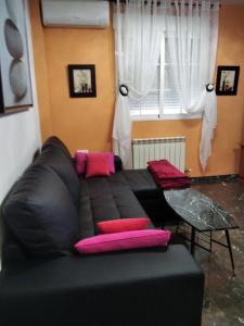 a black couch with pink pillows in a living room at Aurora... Pisos en alquiler Granada. Armilla in Armilla