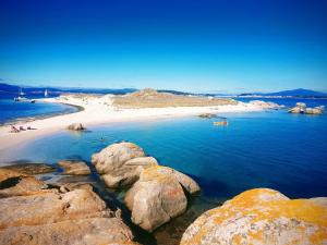 una playa con rocas grandes y el océano en Apartamento Rodeira, en A Illa de Arousa