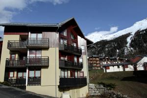 ein Gebäude mit Balkonen und einem schneebedeckten Berg in der Unterkunft le burel la triade 4 personnes in Lanslevillard