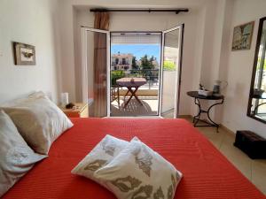 a bedroom with a red bed and a balcony with a table at Seaside Villa Clio in Skála Nikíta