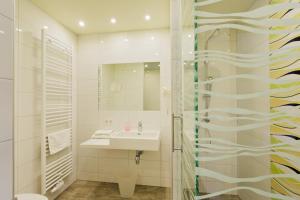 ein weißes Badezimmer mit einem Waschbecken und einem Spiegel in der Unterkunft Motel Baden in Baden