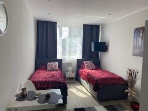 a bedroom with two beds and a table and a window at Business Appartement Mainz Duo in Mainz +21 photos