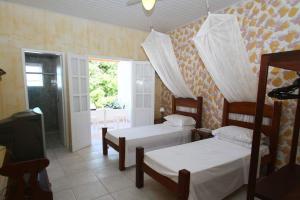 a bedroom with two beds and a tv and a window at Pousada Canavieiras Frederic in Canavieiras