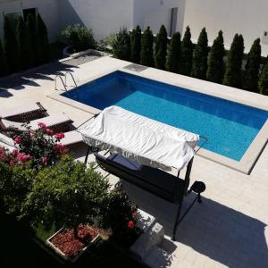 a swimming pool with a white umbrella next to a swimming pool at Apartments Jankovic in Vodice