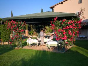 Ein Mann steht in einem Garten mit Tischen und Blumen. in der Unterkunft Relais Osteria Dell'Orcia in Bagno Vignoni