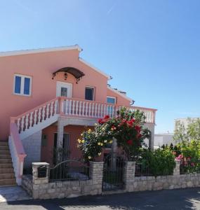 a pink house with a balcony and flowers at Apartments Jankovic in Vodice