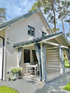 a small white house with a table and chairs at AJ Apartments in Pobierowo