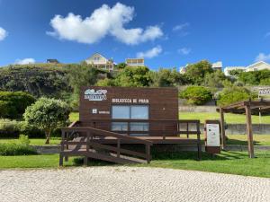 a building with a sign in the grass at White Beach House in Praia da Areia Branca