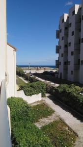einen Fußweg neben einem Gebäude neben dem Strand in der Unterkunft Appartement T2 Ensoleillé au Barcarès in Le Barcarès