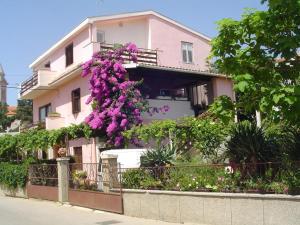 uma casa cor-de-rosa com flores roxas ao lado em Apartment in Pakoštane with sea view, balcony, WiFi (3539-1) em Pakoštane