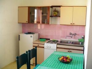 a kitchen with a table with a bowl of fruit on it at Apartment in Pakoštane with sea view, balcony, WiFi (3539-1) in Pakoštane