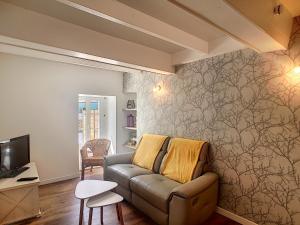 a living room with a couch and a tv at petite maison proche centre ville in Bréhal