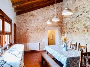 a dining room with a table and a stone wall at Alojamiento Gaia in Aldeasoña