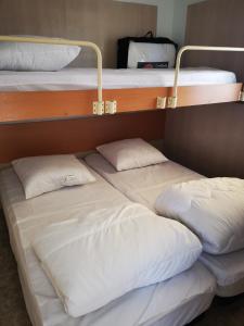 2 łóżka piętrowe z białymi poduszkami w pokoju w obiekcie Cocoon mobil home w mieście Saint-Aygulf