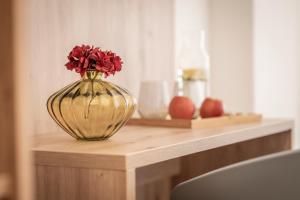Un jarrón con flores rojas en él sentado en un mostrador en Hotel Restaurant Urweider, en Innertkirchen