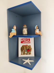 a blue shelf with a book and figurines on it at Apartman Marina II in Rogoznica