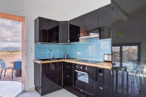 a kitchen with black cabinets and a blue tile wall at Opuntia (Pech) location en Méditerranée in Escales