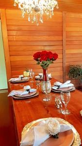 a wooden table with red roses in a vase on it at Recanto Della Mata in Venda Nova do Imigrante