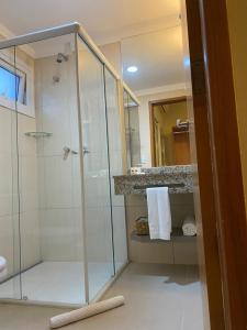 a bathroom with a shower and a glass shower stall at Hotel Porto Real Aparecida in Aparecida