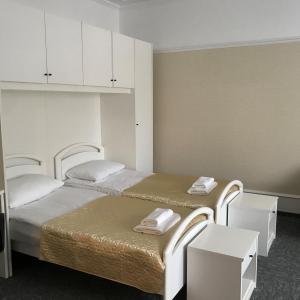 2 camas en una habitación con armarios blancos y toallas en Baza Otdykha Ozero Zerkalnoe, en Poselok Zerkalniy