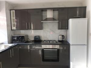 ダートフォードにあるJDB Dartford 2-Bedroom Houseの黒いキャビネットと白い冷蔵庫のあるキッチン