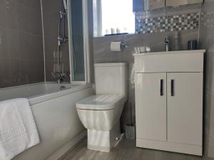 a bathroom with a toilet and a tub and a sink at JDB Dartford 2-Bedroom House in Dartford