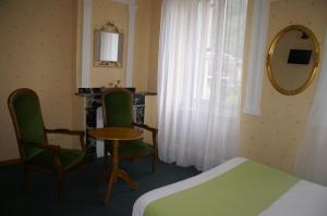 a bedroom with a bed and a table and chairs at Hôtel Céleste in Luchon