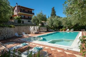 a swimming pool in a yard with chairs and a building at Evridiki's Villas in Agios Nikitas