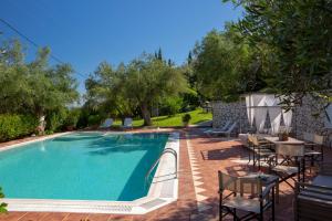 a swimming pool with chairs and a table and some trees at Evridiki's Villas in Agios Nikitas