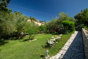 a garden with a table and chairs in the grass at Evridiki's Villas in Agios Nikitas