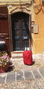 una valigia rossa seduta di fronte a un edificio con una porta di Aigua ad Alghero