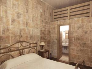 Perimenis Seaside House في ييروميلين: غرفة نوم بسرير وجدار حجري