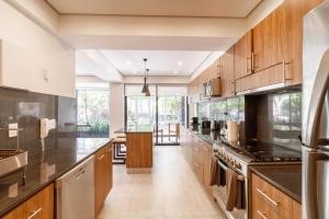 a large kitchen with wooden cabinets and black counter tops at Luxury 3BD Apartment with Patio in Mexico City