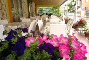 un gruppo di tavoli e sedie con fiori rosa e viola di Hotel Simon a Rimini