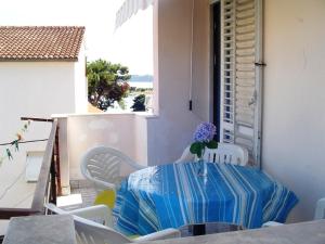 a table and chairs with a vase of flowers on a balcony at Apartment in Pakoštane with sea view, balcony, WiFi (3539-2) in Pakoštane