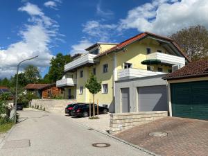 une maison jaune avec un garage et une allée dans l'établissement Haus Langweid - Moderne Ferienwohnungen mit Luxus im Inntal, à Neubeuern