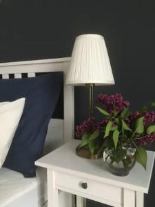 a table with a lamp and a vase of purple flowers at Dominique Apartment in Krakow