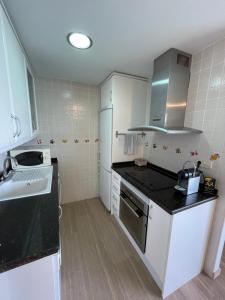 a kitchen with white cabinets and a black counter top at CLP- Primera linea vistas piscina y parking in Calpe