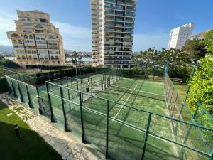 a tennis court in front of a tall building at CLP- Primera linea vistas piscina y parking in Calpe