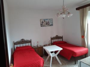 two beds in a room with red sheets and a table at Affittacamere da Angela in Borgorose