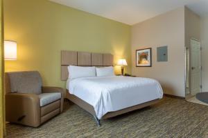 Habitación de hotel con cama y silla en Candlewood Suites South Bend Airport, an IHG Hotel, en South Bend