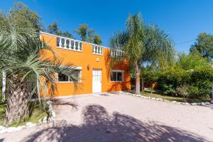 une maison orange avec des palmiers devant elle dans l'établissement Las Coloniales, à Sauce de Portezuelo