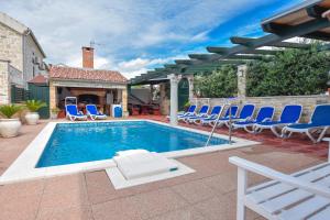 a swimming pool with blue chairs and a patio at Apartments Jacqueline in Pakoštane