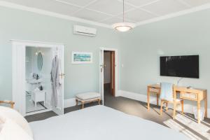 a bedroom with a bed and a desk and a tv at Cedar House in Gisborne