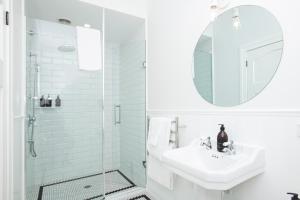a white bathroom with a sink and a mirror at Cedar House in Gisborne