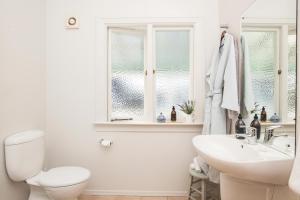 a white bathroom with a toilet and a sink at Cedar House in Gisborne