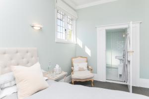 a white bedroom with a bed and a chair at Cedar House in Gisborne