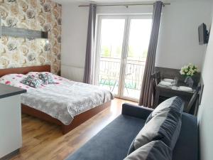 een slaapkamer met een bed, een bank en een raam bij Villa Over Lake in Mielno