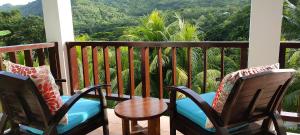 a balcony with two chairs and a table and a view at Chalets Des Vacances in Takamaka