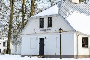 uma casa branca na neve com uma luz de rua em Zyplių Dvaro Oficina Viešbutis 
